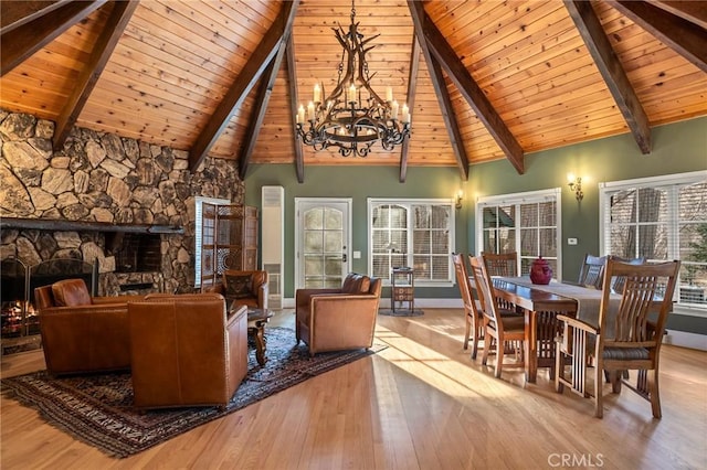 interior space featuring wooden ceiling, a notable chandelier, lofted ceiling with beams, and a stone fireplace