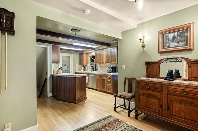 kitchen with stainless steel dishwasher, backsplash, beamed ceiling, and light hardwood / wood-style flooring