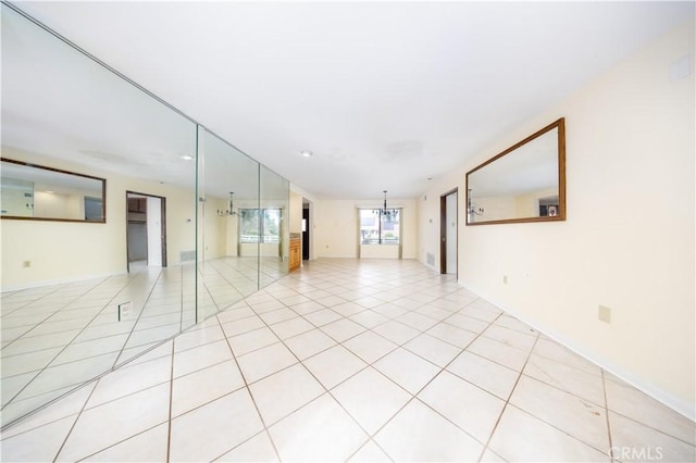 unfurnished room with an inviting chandelier and light tile patterned flooring