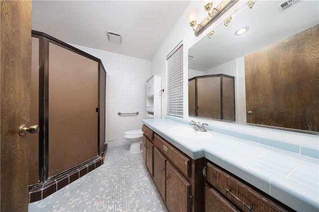 bathroom featuring toilet, vanity, tile patterned floors, and walk in shower