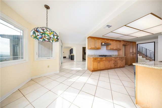 kitchen with black gas stovetop, backsplash, pendant lighting, light tile patterned flooring, and light stone countertops