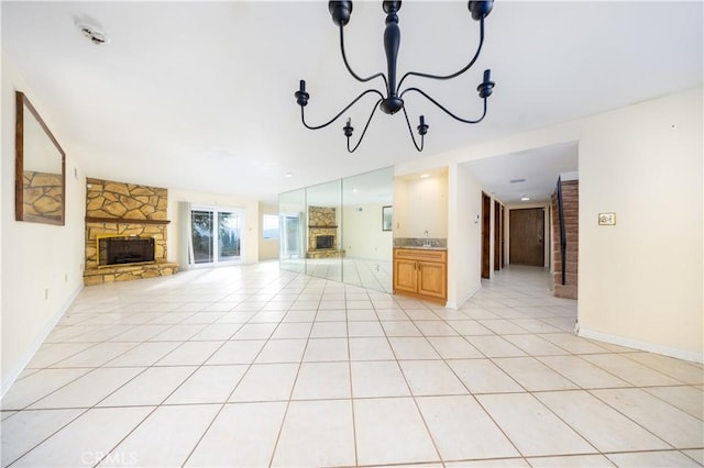 unfurnished living room with a notable chandelier, light tile patterned flooring, and a stone fireplace