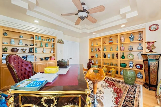 recreation room featuring light hardwood / wood-style floors, ceiling fan, and a raised ceiling