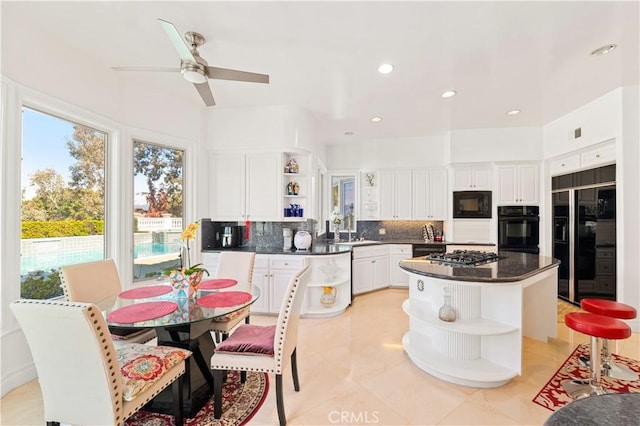 kitchen featuring a kitchen island, black appliances, white cabinets, and ceiling fan