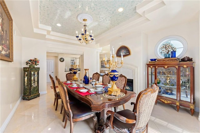 tiled dining space with a textured ceiling, a chandelier, ornate columns, and a raised ceiling