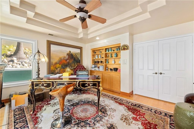 office area featuring built in features, ceiling fan, hardwood / wood-style floors, and a tray ceiling