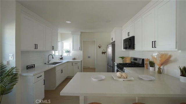 kitchen featuring white cabinetry, stainless steel appliances, sink, kitchen peninsula, and a breakfast bar