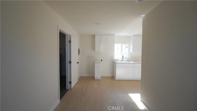 corridor with sink and light hardwood / wood-style flooring