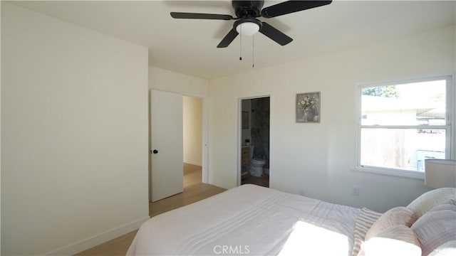 bedroom featuring ceiling fan, multiple windows, ensuite bathroom, and light hardwood / wood-style flooring