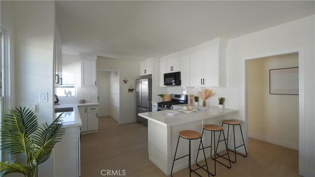 kitchen featuring backsplash, kitchen peninsula, sink, stainless steel appliances, and white cabinets