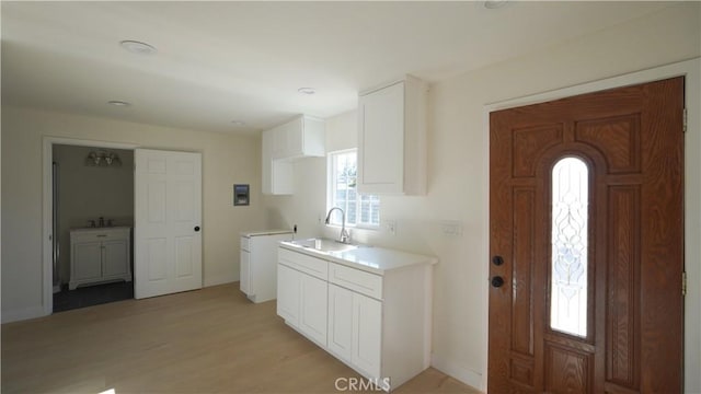 kitchen with light wood-type flooring, white cabinets, and sink