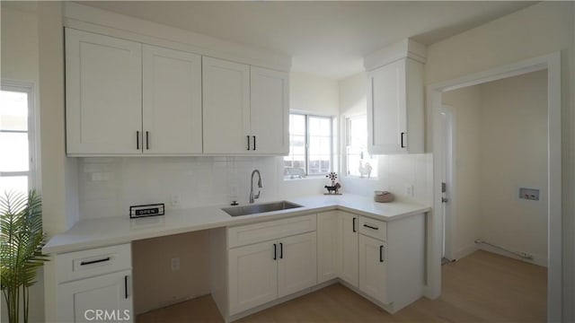 kitchen with decorative backsplash, sink, white cabinetry, and light hardwood / wood-style floors