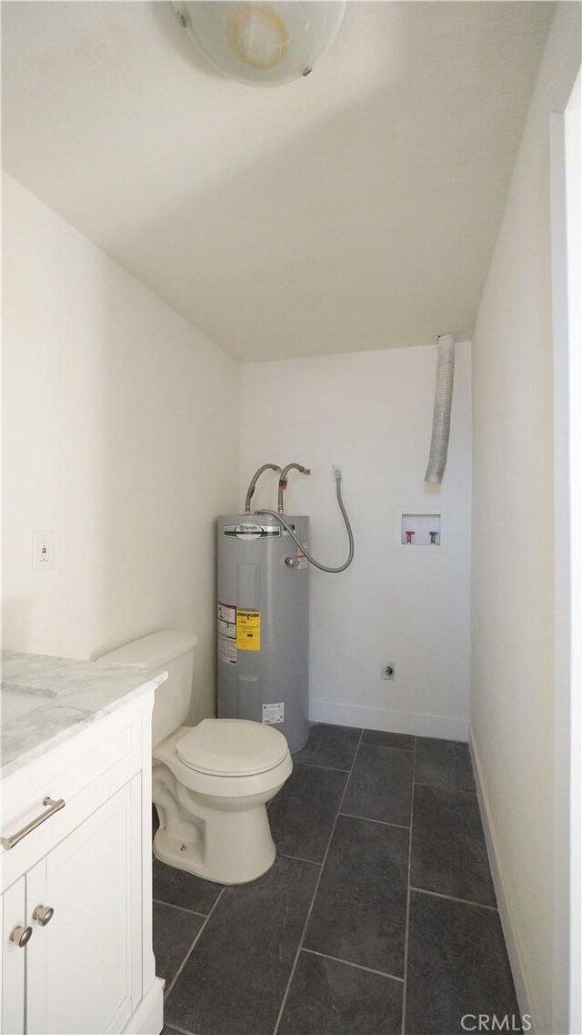 bathroom with toilet, vanity, water heater, and tile patterned flooring