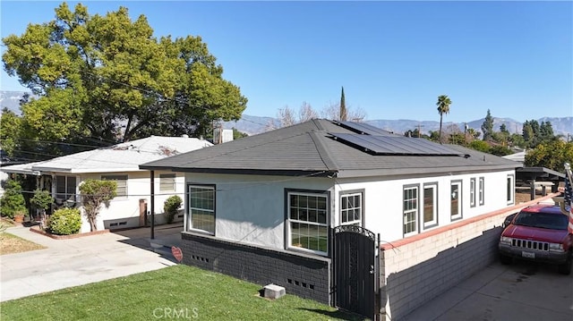 view of side of property featuring a lawn, a mountain view, and solar panels