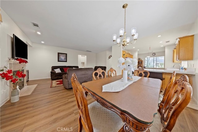 dining space with light hardwood / wood-style flooring and a notable chandelier