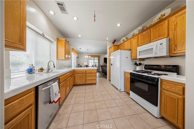 kitchen with kitchen peninsula, sink, white appliances, light tile patterned flooring, and hanging light fixtures