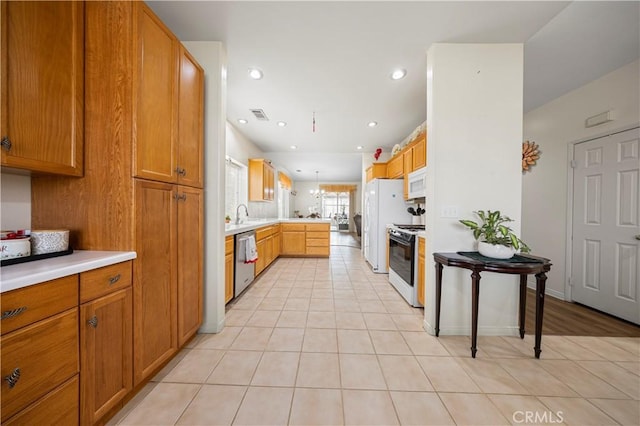 kitchen featuring pendant lighting, kitchen peninsula, a kitchen bar, light tile patterned flooring, and white appliances