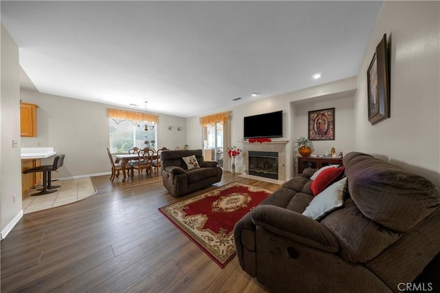 living room with an inviting chandelier, light hardwood / wood-style flooring, and a tiled fireplace