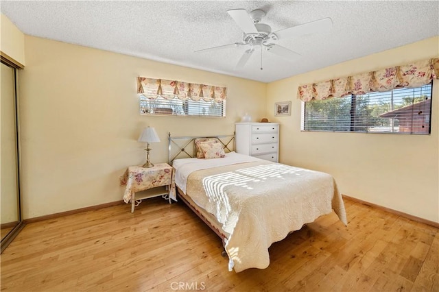 bedroom with ceiling fan, light hardwood / wood-style floors, a closet, and a textured ceiling