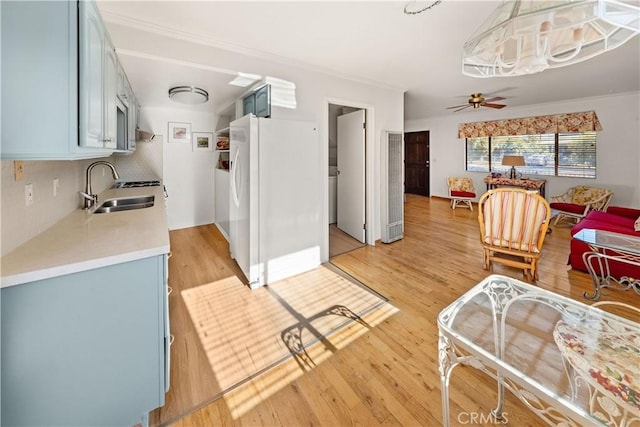 living room with ceiling fan, sink, and light wood-type flooring