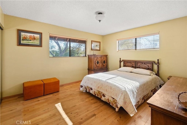 bedroom featuring multiple windows, a textured ceiling, and light wood-type flooring