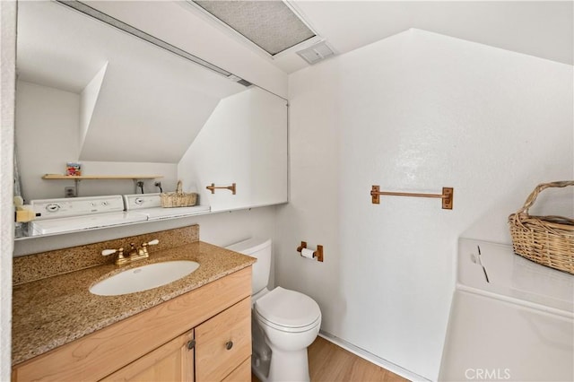 bathroom featuring hardwood / wood-style flooring, washing machine and dryer, vanity, and toilet