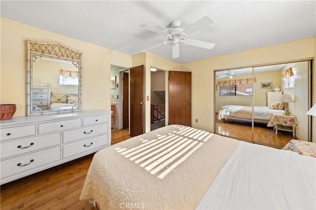 bedroom featuring connected bathroom, hardwood / wood-style floors, ceiling fan, a textured ceiling, and a closet