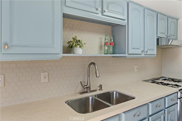 kitchen with decorative backsplash, blue cabinets, sink, and white range with gas stovetop