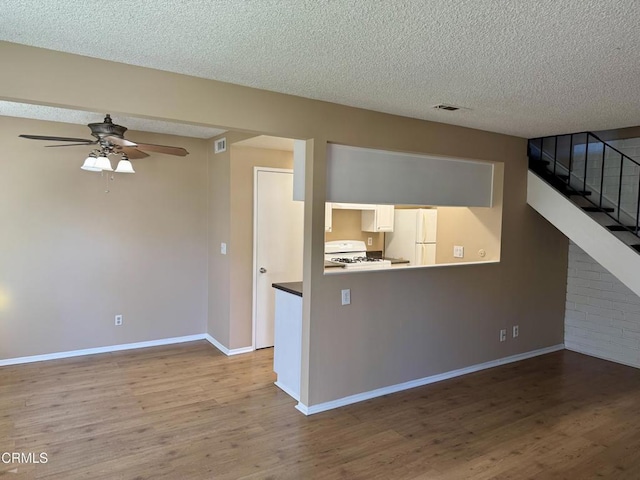 unfurnished living room with a textured ceiling, ceiling fan, and hardwood / wood-style flooring