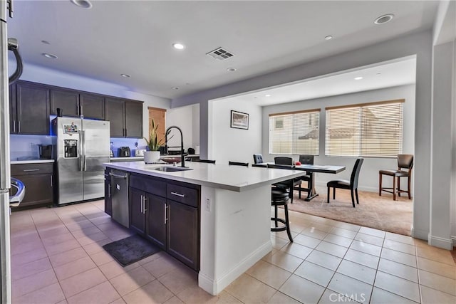 24469 Paxton Ln, Lake Elsinore, CA 92532 - kitchen with stainless steel appliances, light countertops, light tile patterned floors, a breakfast bar area, and a kitchen island with sink