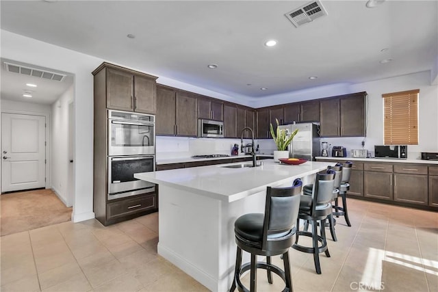 24469 Paxton Ln, Lake Elsinore, CA 92532 - kitchen featuring appliances with stainless steel finishes, dark brown cabinetry, light countertops, a breakfast bar area, and recessed lighting