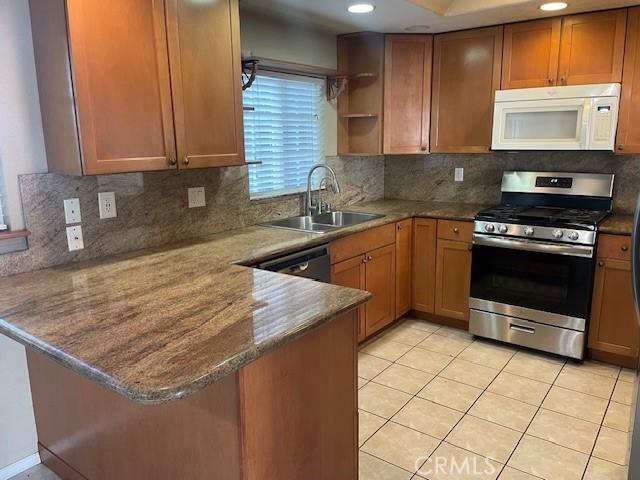 kitchen with tasteful backsplash, sink, kitchen peninsula, and appliances with stainless steel finishes