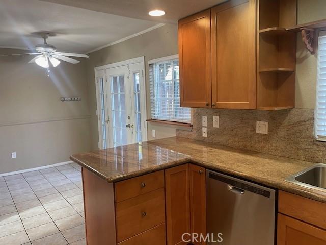 kitchen featuring light tile patterned flooring, tasteful backsplash, dishwasher, ceiling fan, and light stone counters