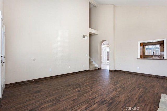 unfurnished living room featuring dark wood-type flooring and high vaulted ceiling