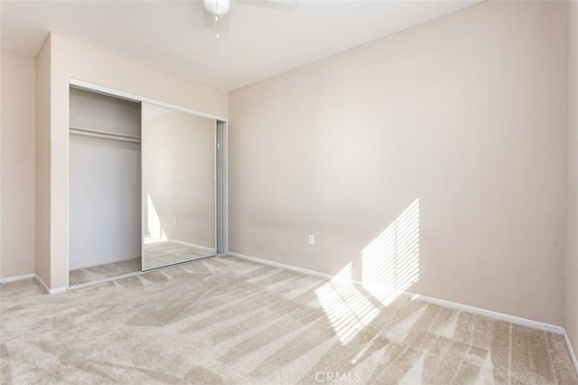 unfurnished bedroom featuring light carpet, a closet, and ceiling fan