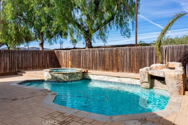 view of swimming pool with a patio area, pool water feature, and an in ground hot tub