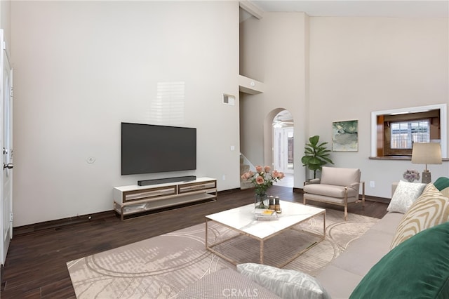 living room with plenty of natural light, dark hardwood / wood-style flooring, and a high ceiling