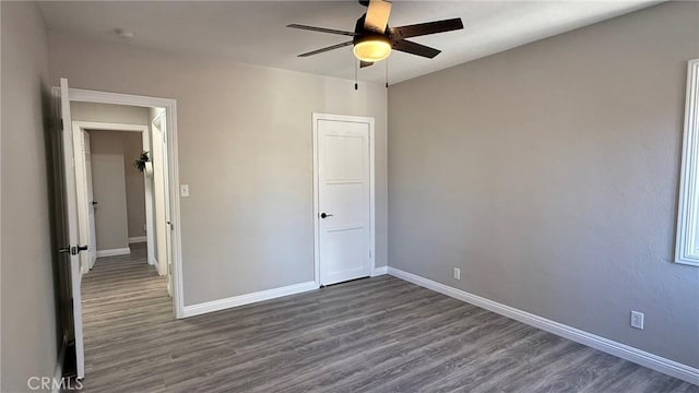 unfurnished bedroom with ceiling fan and dark wood-type flooring