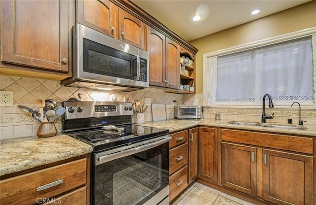 kitchen with decorative backsplash, sink, stainless steel appliances, and light stone countertops