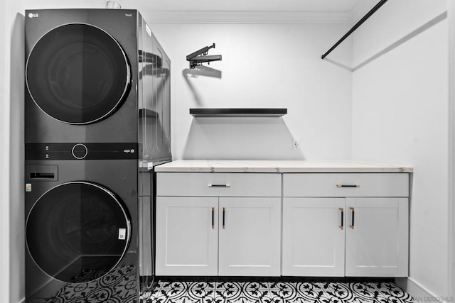 washroom featuring stacked washer / drying machine, ornamental molding, and cabinets