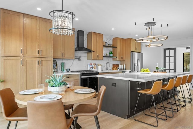 kitchen with a kitchen island, decorative backsplash, stainless steel fridge with ice dispenser, wall chimney exhaust hood, and range with gas stovetop