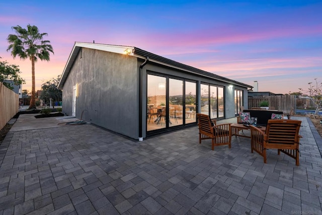 back house at dusk featuring an outdoor hangout area and a patio