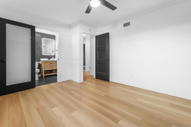 unfurnished bedroom featuring ceiling fan, crown molding, connected bathroom, and light hardwood / wood-style flooring