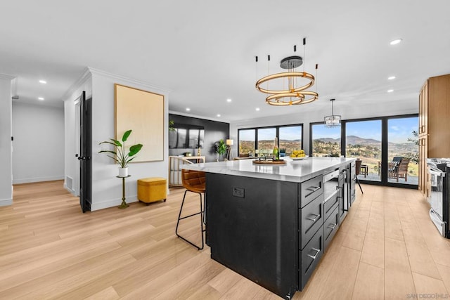 kitchen with decorative light fixtures, a kitchen island, light wood-type flooring, ornamental molding, and a chandelier