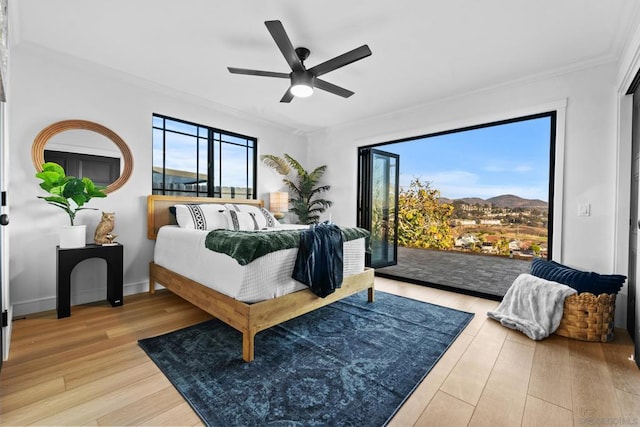 bedroom featuring ceiling fan, hardwood / wood-style floors, ornamental molding, and a mountain view