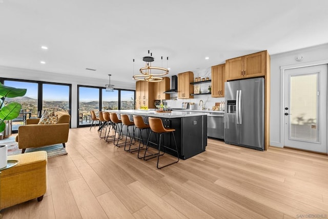 kitchen featuring appliances with stainless steel finishes, decorative light fixtures, a kitchen breakfast bar, wall chimney range hood, and a kitchen island