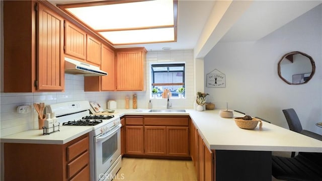 kitchen featuring a kitchen bar, sink, kitchen peninsula, and white gas range oven