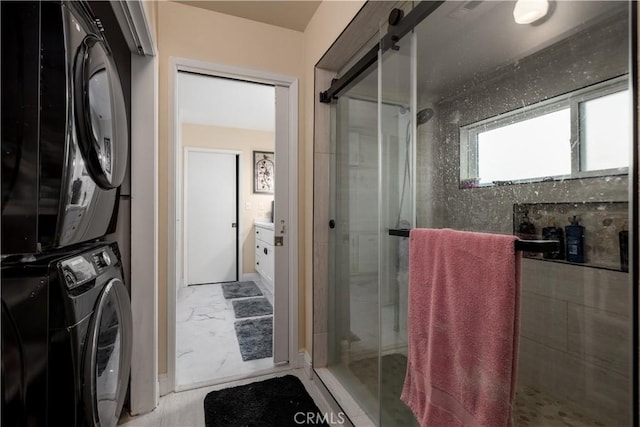 bathroom with a shower with shower door and stacked washer and dryer