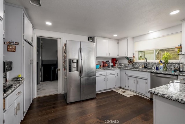 kitchen featuring light stone countertops, appliances with stainless steel finishes, sink, white cabinets, and dark hardwood / wood-style flooring