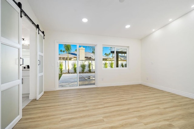 unfurnished room featuring a barn door and light wood-type flooring